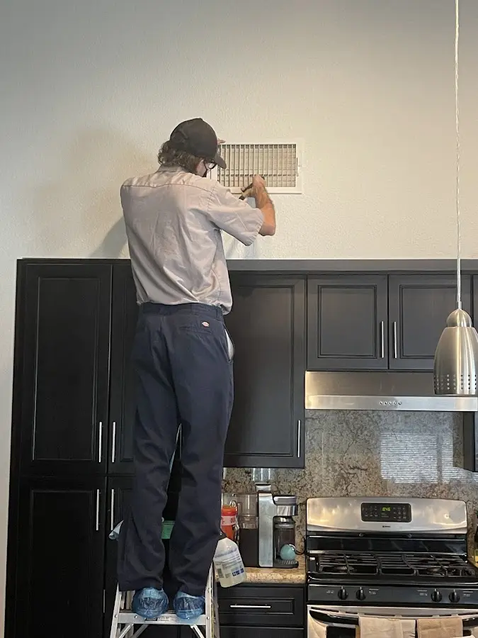 Technician inspecting an air vent during HVAC service in Niagara